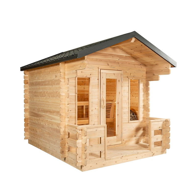 A large, outdoor, cedar cabin sauna with two windows, a glass door, a black metal roof and a porch.