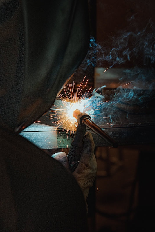 A man welding a steel, wood-burning sauna stove.