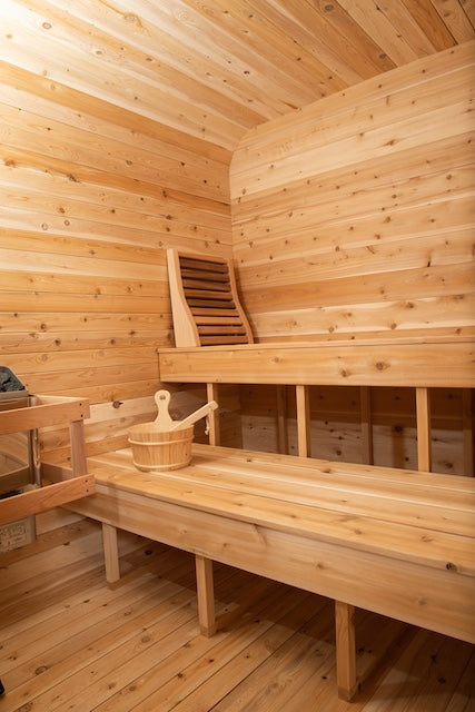 The inside of a Henki Cube Sauna with a bucket, ladle, and Henki Lumbar Back rest on the benches.