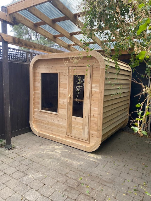 A covered Henki Cube Sauna in a backyard.