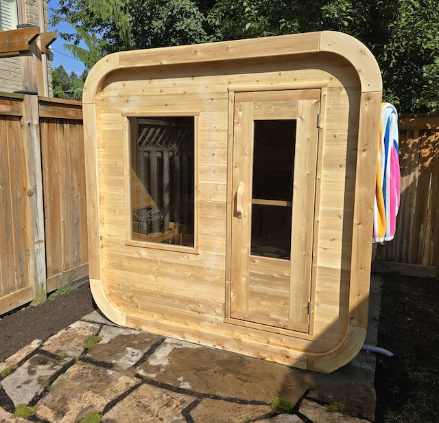 The front of a Henki Cube Sauna on patio stones in a Toronto backyard.