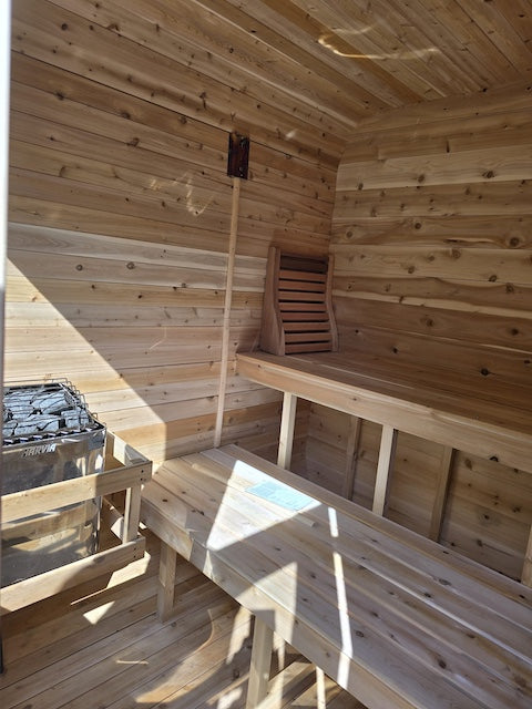 The cedar interior of a Henki Cube Sauna with a Harvia sauna heater and a Henki Lumbar Back Rest. 