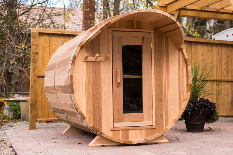 A Henki Custom Barrel Sauna made from clear red cedar with a cove roof overhang on a patio in Toronto.