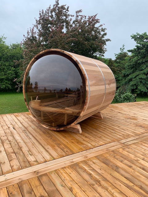A Henki Custom Barrel Sauna with a large panoramic dome window on a large deck.