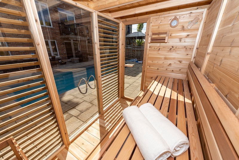 The interior of a Custom Pure Cube Sauna from Henki Sauna Co overlooking a pool in a Toronto backyard.
