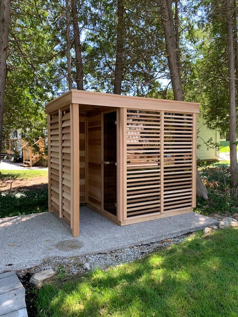 A Custom Pure Cube Sauna with an outdoor shower on a concrete foundation.