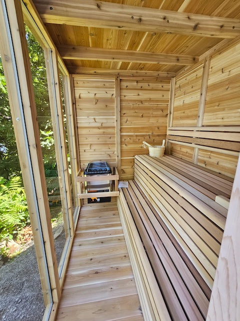 The interior of a Custom Pure Cube Sauna with a sauna bucket and ladle on the benches.