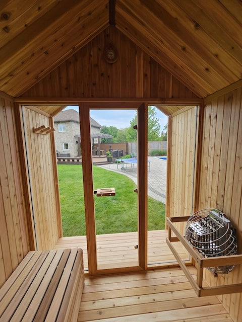The interior of a Pure Cube Hudson Sauna overlooking a backyard with a pool in Ontario.