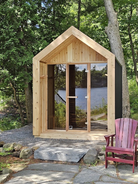 The front of a Pure Cube Hudson Sauna with a red Muskoka chair next to it.