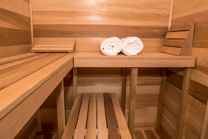 the clear cedar benches inside of a Henki Modern Cabin Sauna with two white rolled towels.