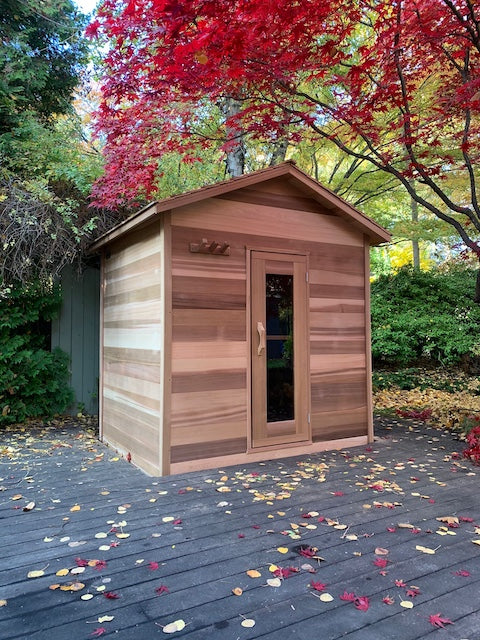 A Henki Modern Cabin Sauna in a Toronto backyard with a red tree over top of it.