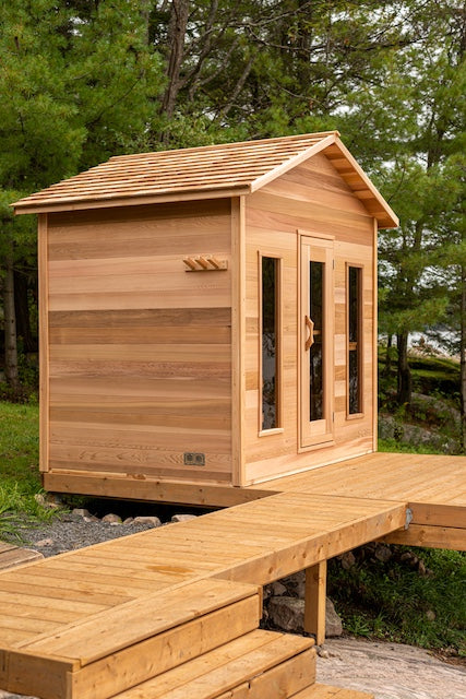 A clear cedar sauna with two windows and a Henki Sauna Door.