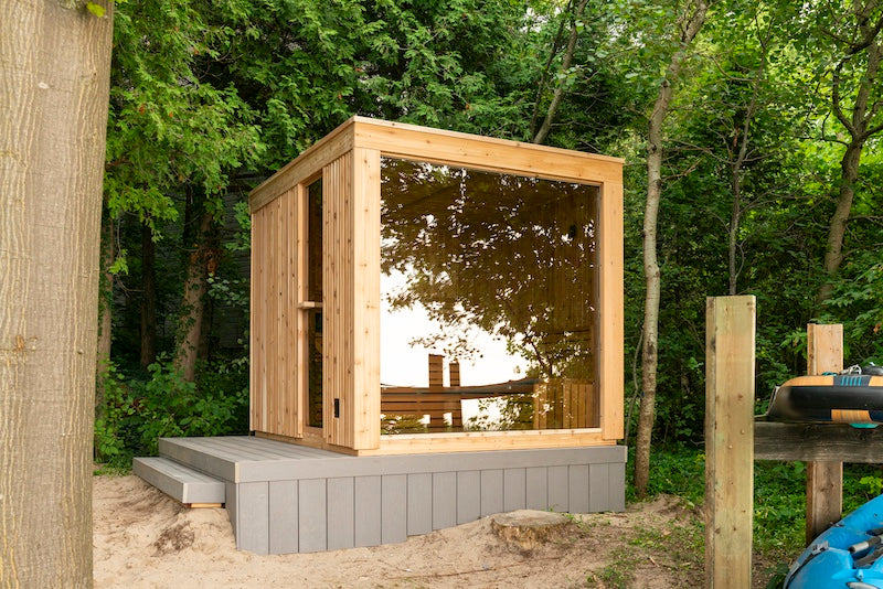 A Pure Cube Neptune Sauna on a small deck next to the forest in Muskoka.