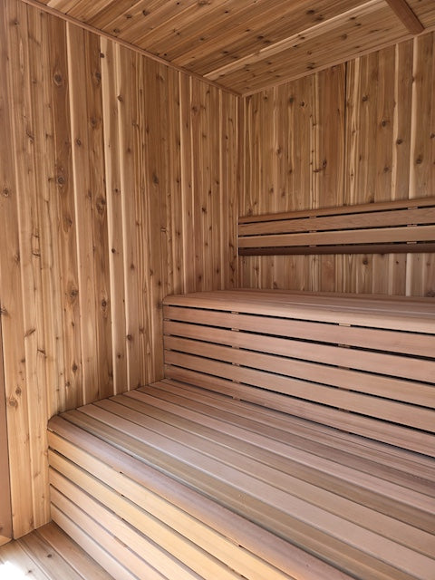 The clear cedar benches and back rest inside of a Pure Cube Neptune Sauna from Henki.