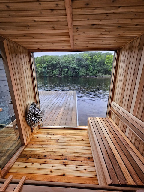 The interior of a cedar sauna with a large glass window on a dock in Muskoka.