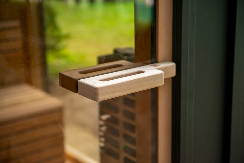 A cedar sauna door handle on Henki's Tempered Glass Sauna Door.