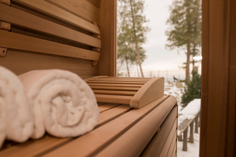 The benches, back rest, and view from the inside of a Henki Panoramic Cube Sauna in the winter. 