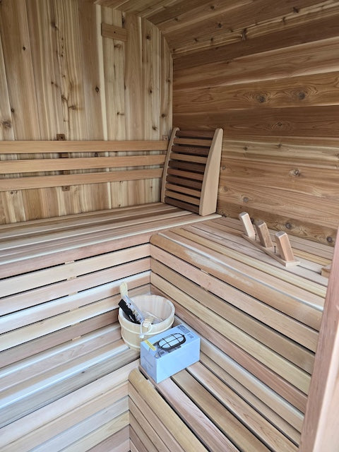 Inside a Panoramic Cube Sauna from Henki with sauna accessories on the cedar benches.